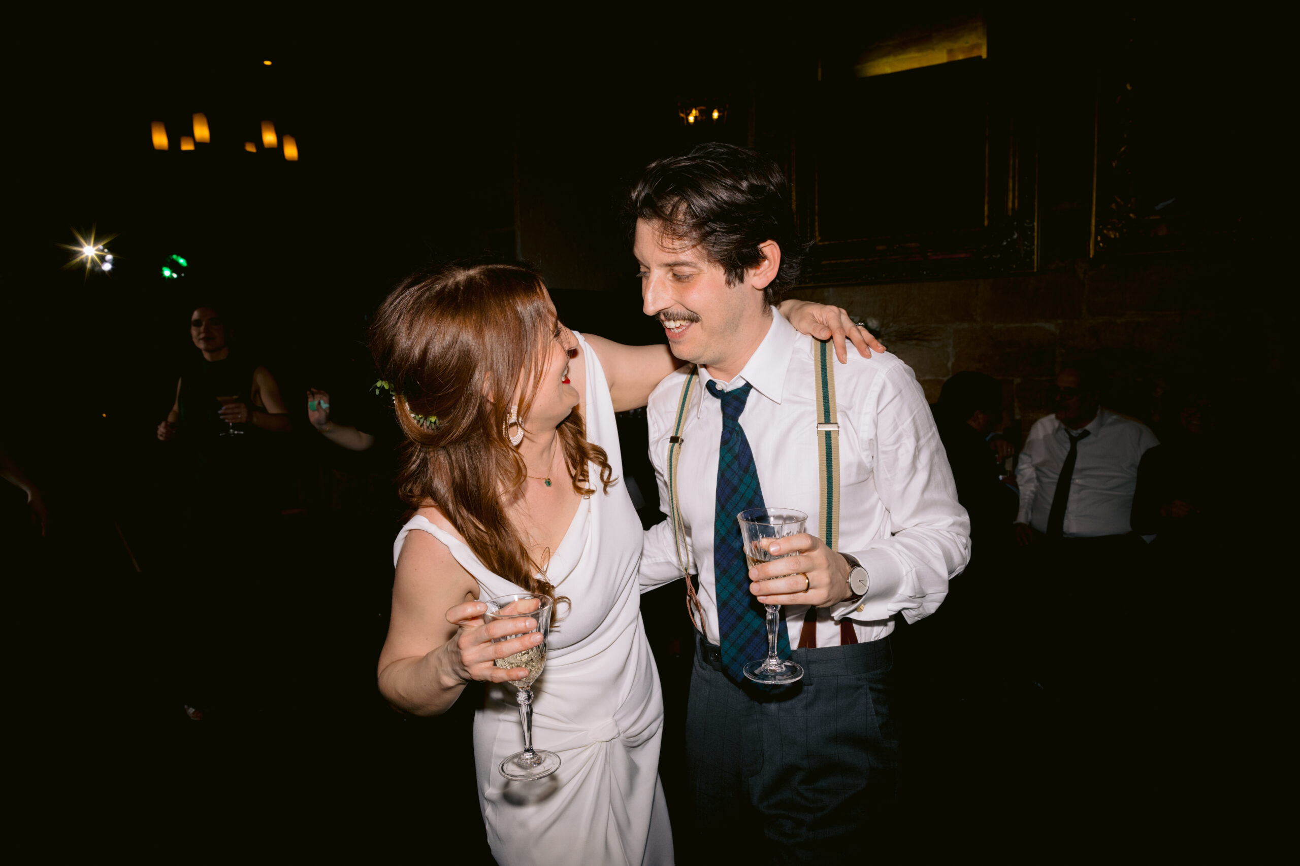 bride and groom on dance floor looking at each other and laughing, bride has arm around grooms neck