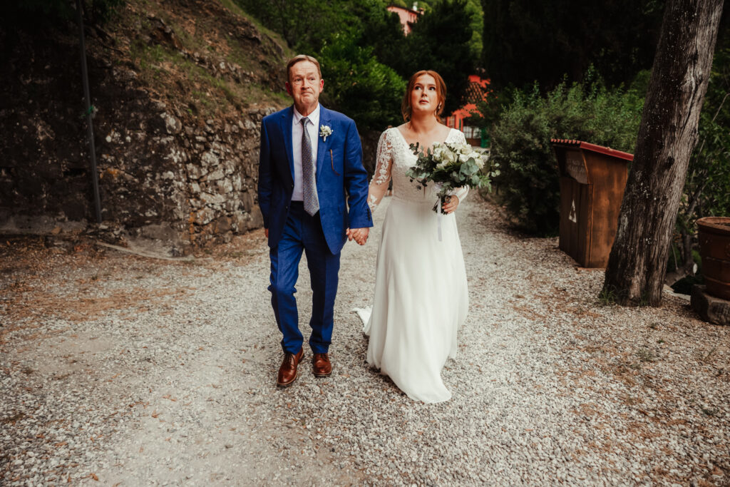 bride and dad look nervous as the walk to hilltop ceremony in Tuscany Italy