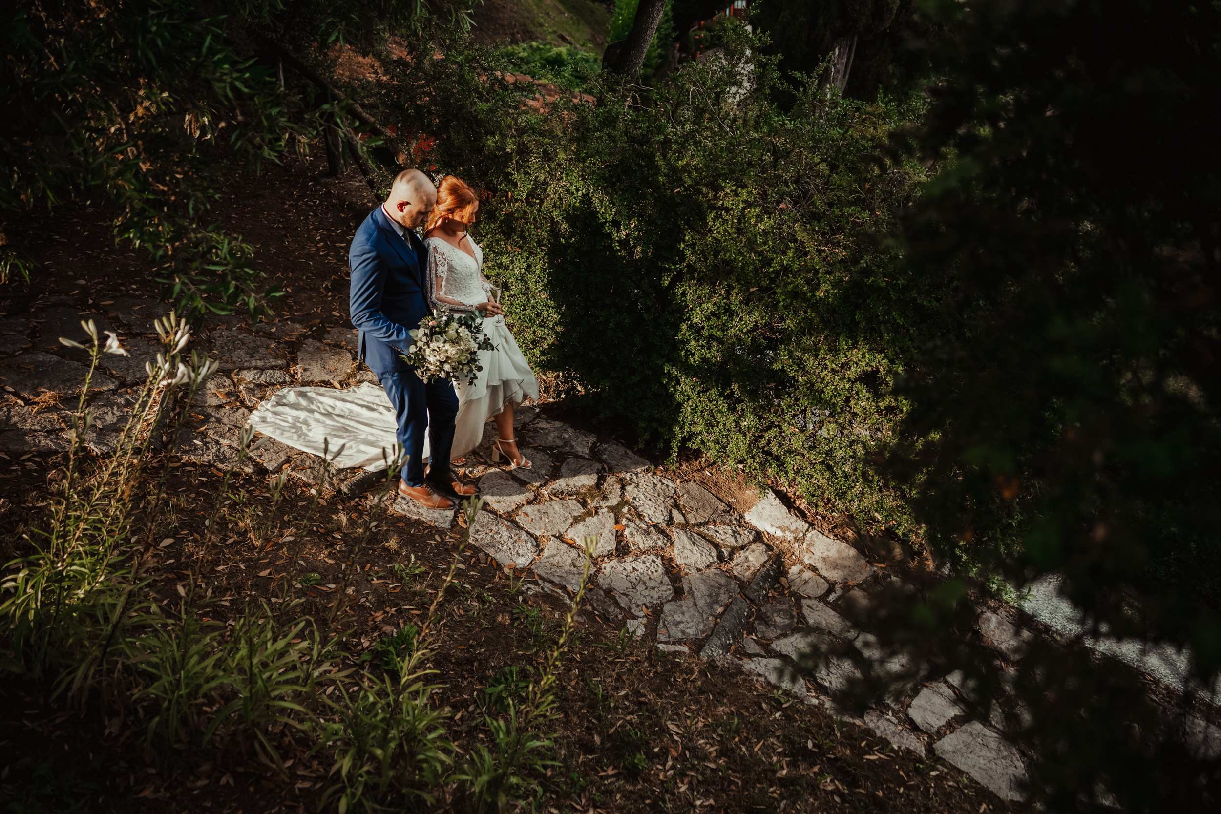 bride and groom walk down sunlit path
