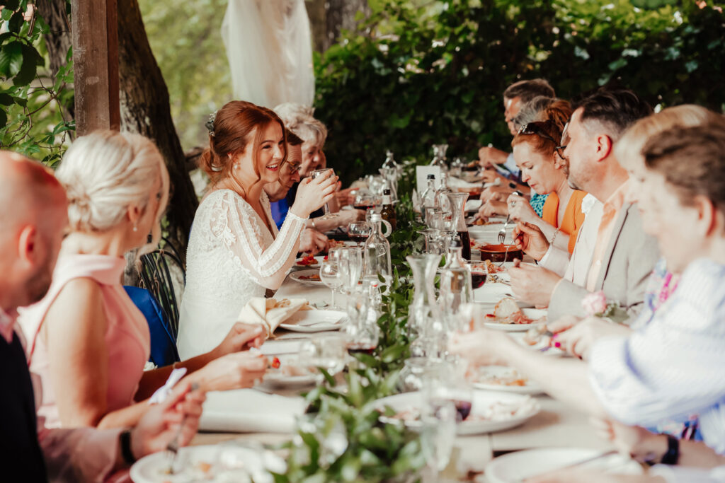 bride smiles and laughs at outdoor dinner iat Italian wedding