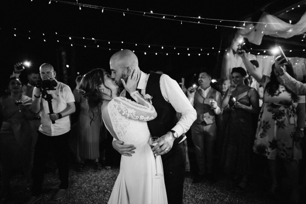 bride and groom kiss while surrounded by guests at Italian destination wedding