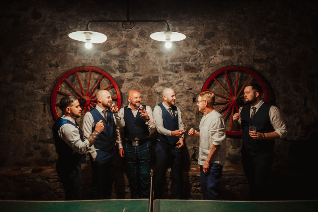 groom and grooms men laugh and smoke cigars